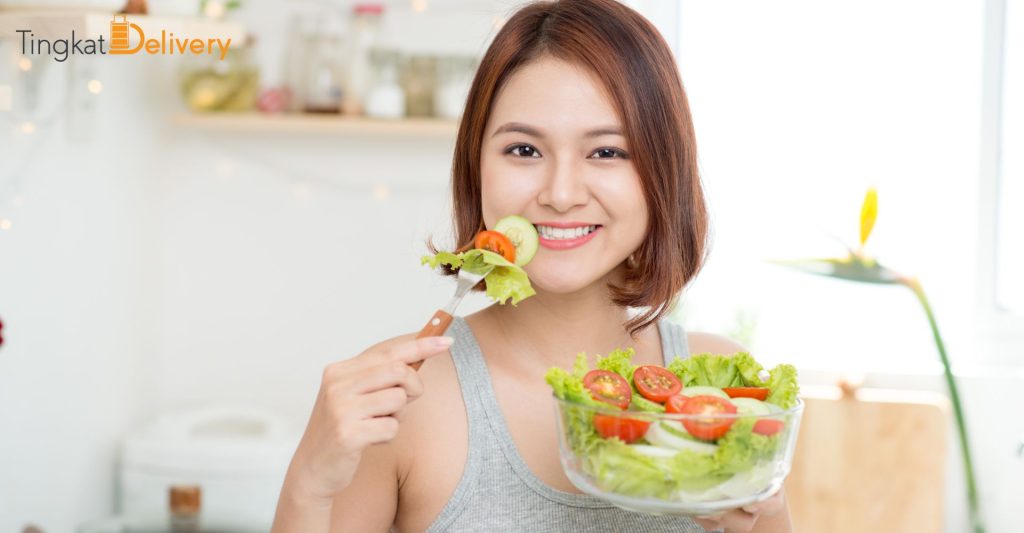 A person eating a healthy meal, such as a salad or a piece of fruit.